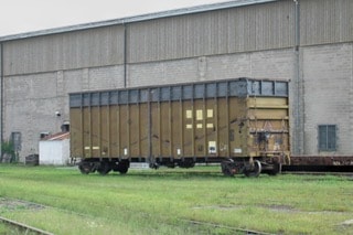 Weathered Altoona gondola car parked outside facility before remanufacturing