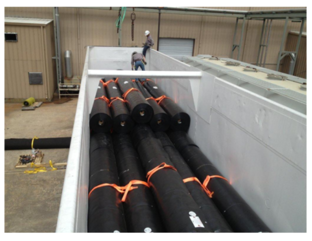 Interior of remanufactured Waste-Gon car loaded with bundled rolls secured with orange straps